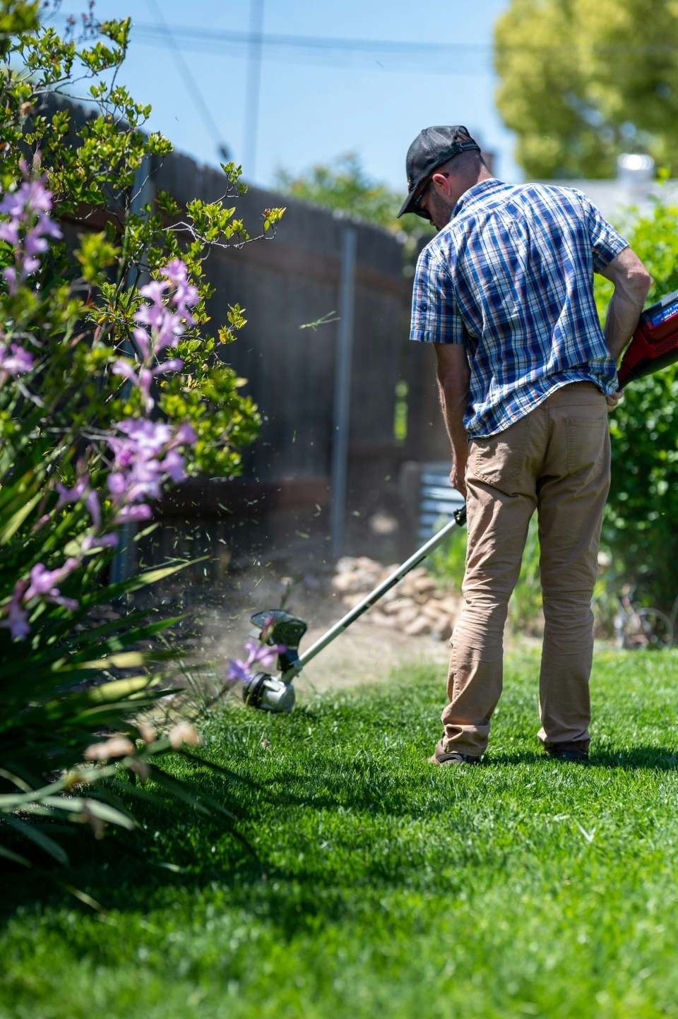 Mann verwendet Rasentrimmgerät, GFL Garten- Forst- undLandschaftspflege GmbH
